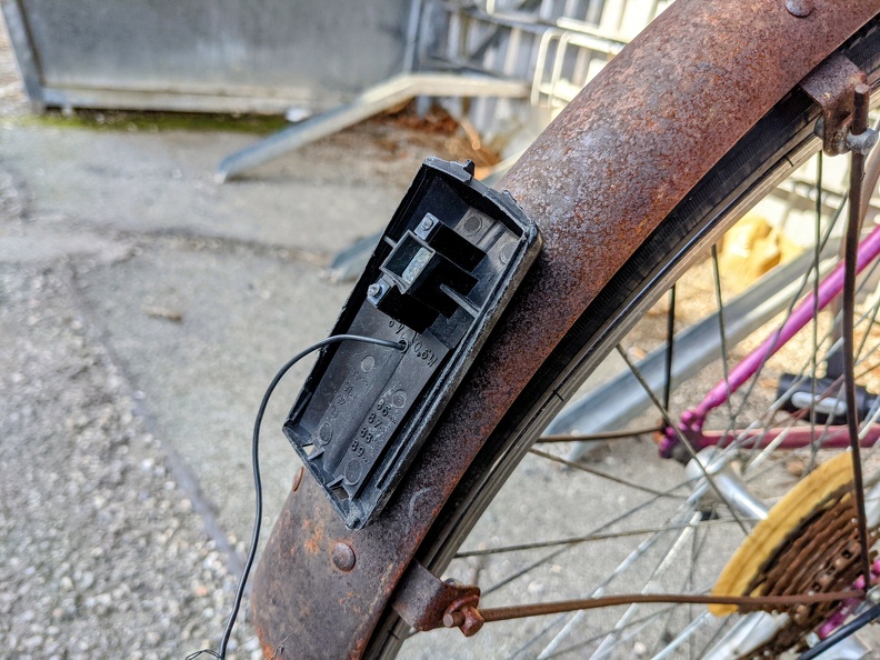 Ein rostiges Schutzblech eines Fahrrads mit einem kaputten Rücklicht. Kaputtes Rücklich am Fahrrad.jpg