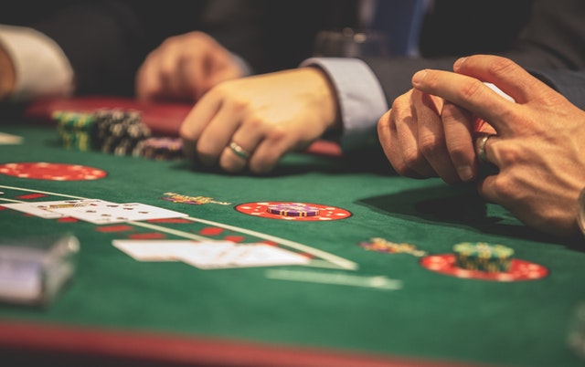 Ein Pokertisch, auf dem mehrere Chips, Karten und Hände der Spieler liegen